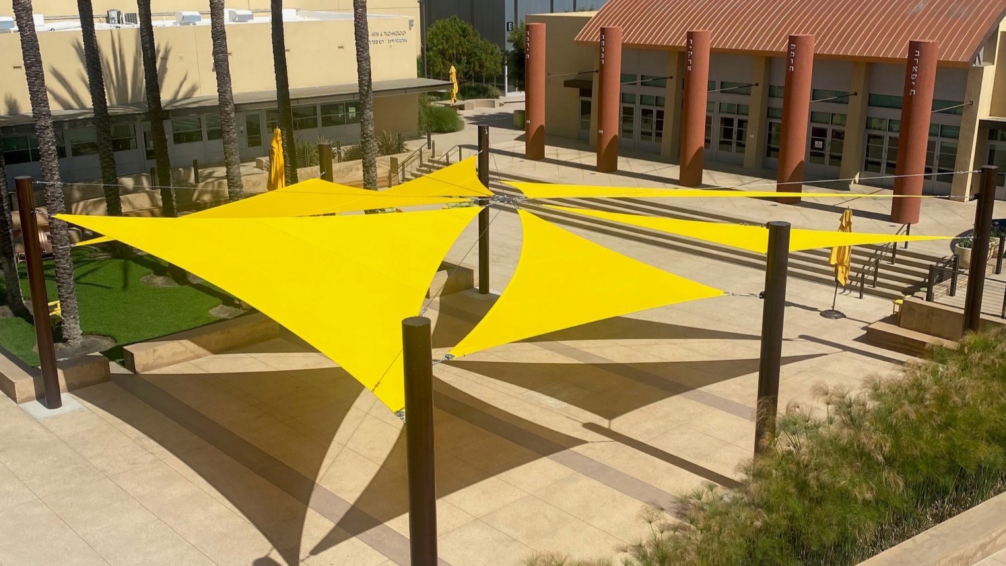 Yellow shade sails for school campuses covering an outdoor courtyard walkway