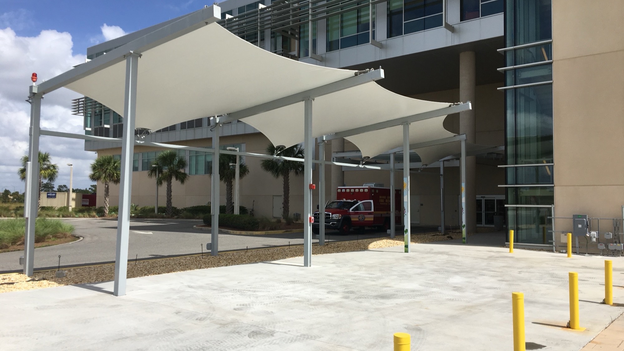 Waterproof Shade Structures HDPE Mesh vs PVC Membrane Waterproof shade structures with PVC membrane over a hospital ambulance bay entrance