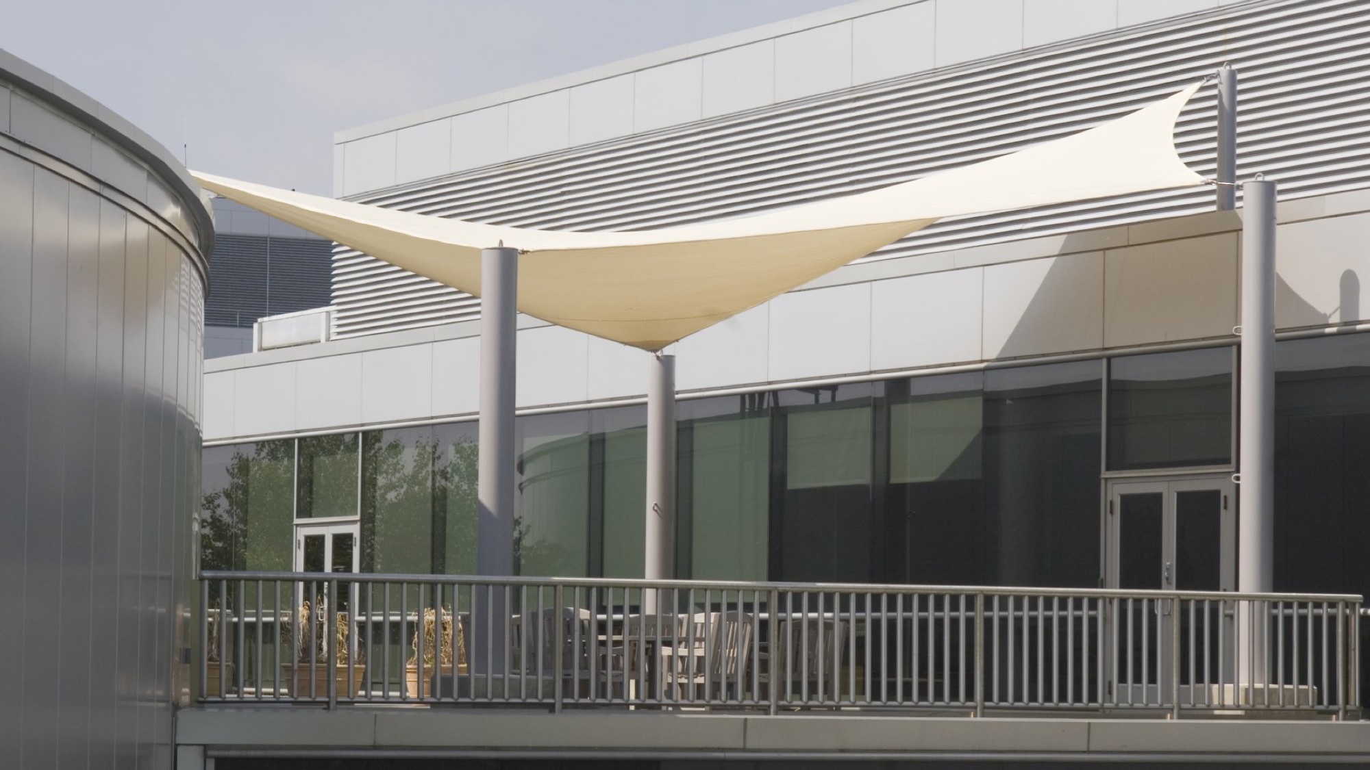 Rooftop bar shade structure: tensioned fabric sail over a rooftop deck dining area