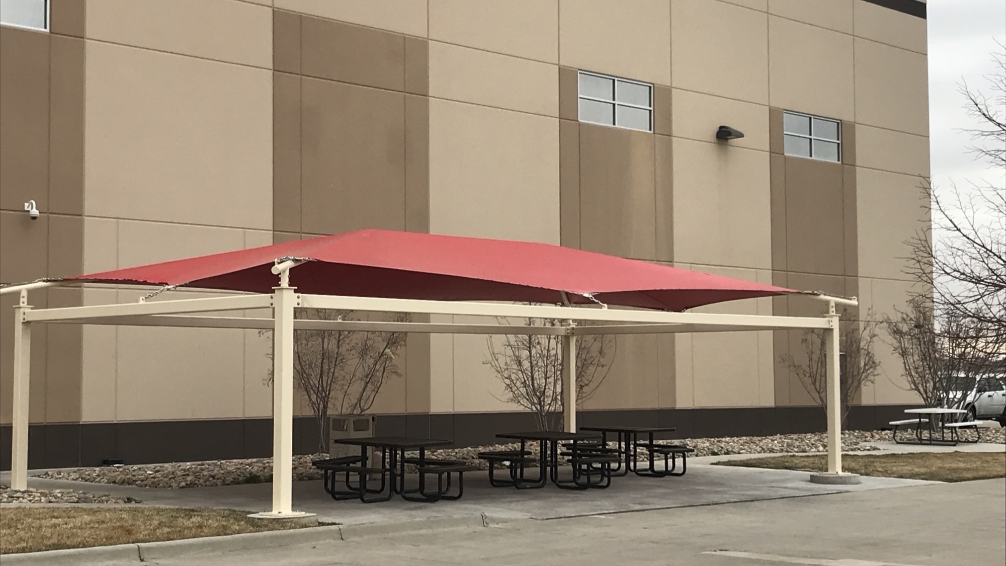 Shaded employee break area with picnic tables at a distribution center facility, an example of shade structures for distribution centers