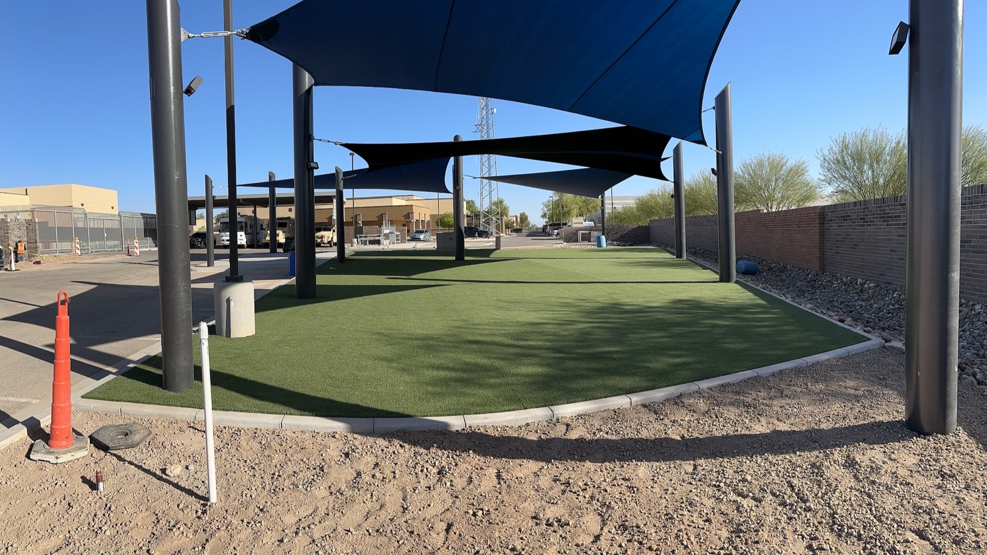 Commercial shade sail installation with tensioned fabric sails over a facility yard