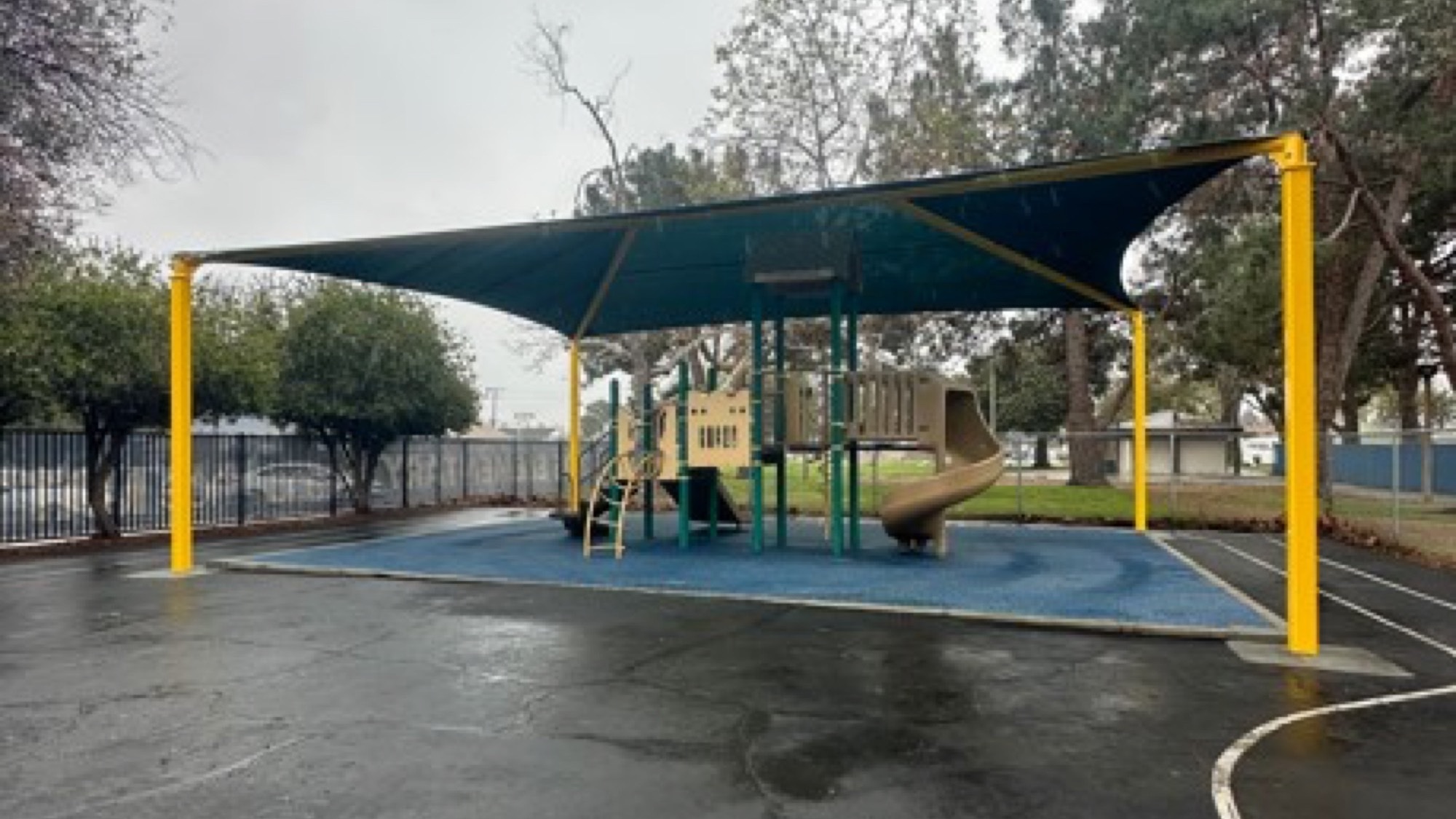 Playground shade structure retrofit with hip canopy installed over existing play equipment